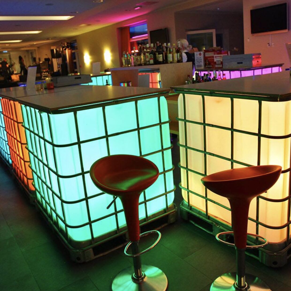 Eight shirts arranged on table in black, olive, grey, blue, white, red, mustard, and green.